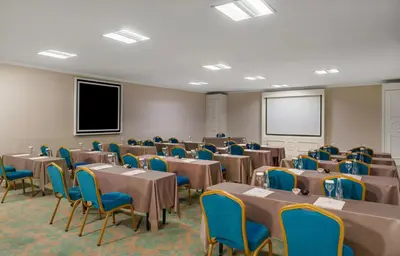 a conference room with tables and chairs and a screen at Kaya İstanbul Fair & Convention in Istanbul