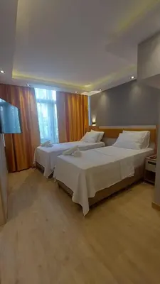 a bedroom with two beds and a large window at Enjoy Suit in Tuzla