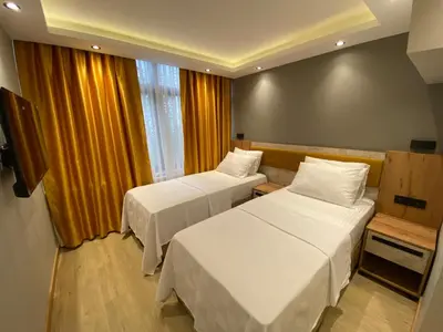a hotel room with two beds and a window at Enjoy Suit in Tuzla