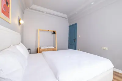 a bedroom with two white beds and a blue door at Mayer Beyoglu Apartments in Istanbul