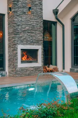 a swimming pool with a fireplace in front of a house at Villa Ulusoy Sapanca in Sapanca