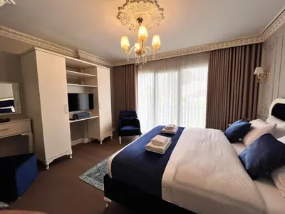 a bedroom with a large bed and a chandelier at Nil Konaklama Sapanca in Sapanca