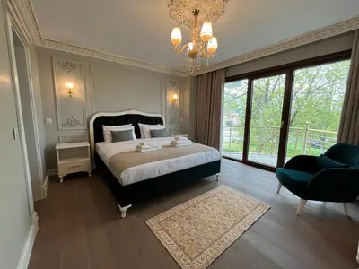 a bedroom with a bed and a chair and a chandelier at Nil Konaklama Sapanca in Sapanca