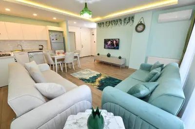 a living room with blue and white couches and a kitchen at Kardes Apartment in Istanbul