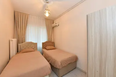 two beds in a small bedroom with a window at Sevim Apartment in Istanbul