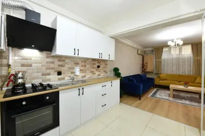 a kitchen with white cabinets and a living room at Bomonti Apartments in Istanbul