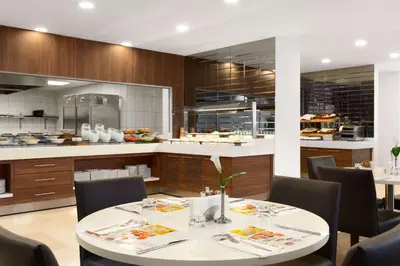 a dining room with a table and chairs and a kitchen at Ramada Encore Istanbul Kartal in Istanbul