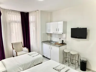 a hotel room with two beds and a kitchen with a sink at Taksim Seven Residence in Istanbul