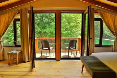 a bedroom with a bed and two chairs on a porch at Lal Hayal Konakları in Sapanca