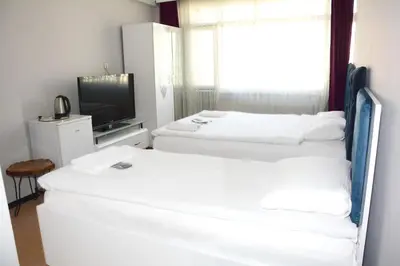 two white beds in a room with a television at palmiye suıt otel in Istanbul