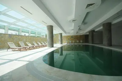 a pool in a building with chairs and a swimming pool at Elite Hotels Darica Spa & Convention Center in Gebze