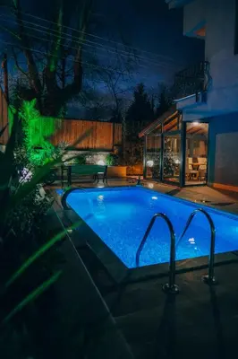 a swimming pool in front of a house at night at Çınar home in Sapanca