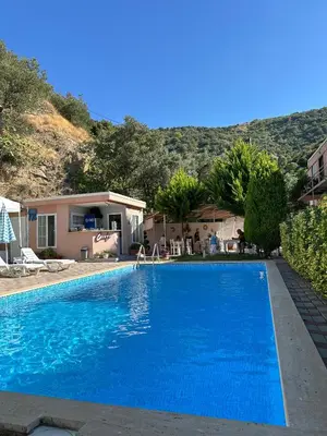a large blue swimming pool in front of a house at Ali Baba Butik Otel in Gündoğdu