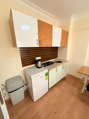 a small kitchen with white cabinets and a trash can at Haliç Konaklama in Istanbul