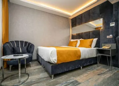 a hotel room with a bed and a chair at 216 Silver Suite in Tuzla