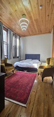 a bedroom with a bed and two chairs and a red rug at Grand Bedir in Istanbul