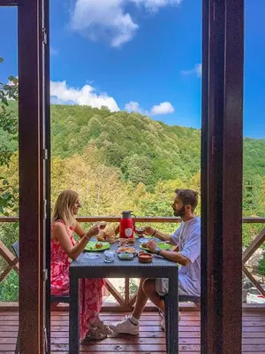 a man and a woman sitting at a table on a porch at Şifaköy Bungalov in Sapanca