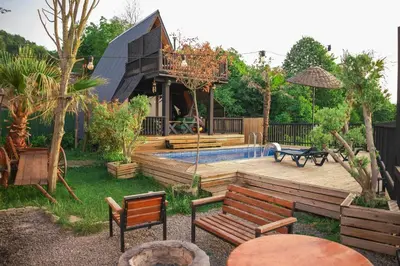 a backyard with a pool and benches and a house at Hill House Bungalov in Sapanca