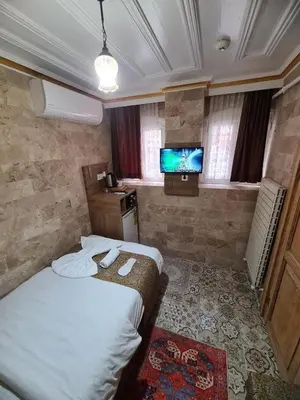 a small room with a bed and a television at Kadıköy White House in Istanbul