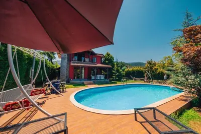 a swimming pool with two chairs and an umbrella at Sapancada ısıtmalı havuzlu villa in Sapanca