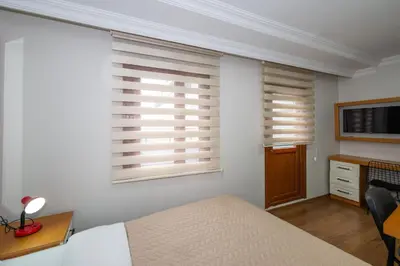 a bedroom with two windows and a bed and a desk at Aras Life Hotel in Istanbul