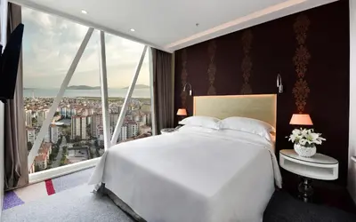 a bedroom with a white bed and a large window at Burgu Arjaan by Rotana Istanbul Asia in Istanbul