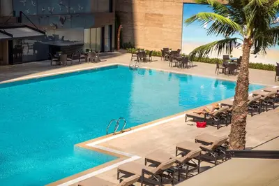 a large swimming pool with chairs and palm trees at Burgu Arjaan by Rotana Istanbul Asia in Istanbul