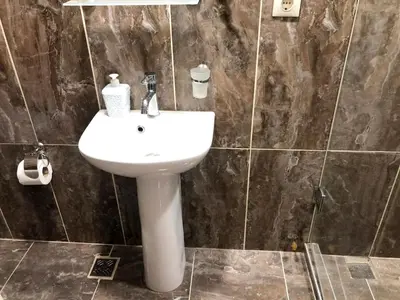 a bathroom with a white sink and a tiled wall at Istanberry - Joker Apartments in Istanbul