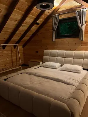 a large bed in a wooden room with a window at Bell Garden Maşukiye in Kocaeli