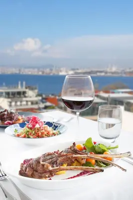 a table with two plates of food and a glass of wine at Sultanahmet Palace Hotel in Istanbul