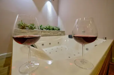 two glasses of wine sitting on a counter with a bath tub at Daire 1 Jakuzili in Beylikduzu
