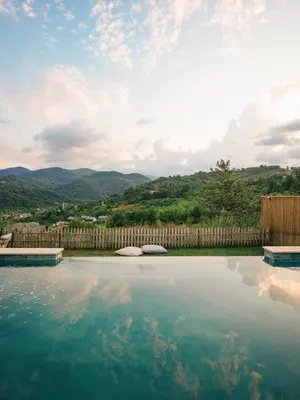 a pool of water with a fence and mountains in the background at Casa Vera Villa in Sakarya