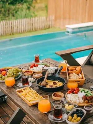 a table full of food and drinks on a table by a pool at Casa Vera Villa in Sakarya