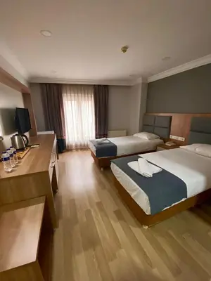 a hotel room with two beds and a desk at Kafkas Hotel Istanbul in Istanbul