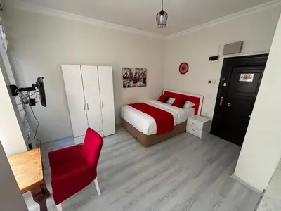 a bedroom with a bed and a red chair at Istanberry - Scarlet Apartments in Istanbul