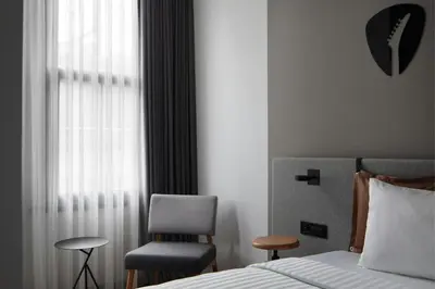 a bedroom with a bed and a chair and a window at Moxy Istanbul Taksim in Istanbul