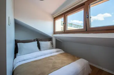 a small bedroom with a bed and two windows at Raya Cihangir Suites in Istanbul