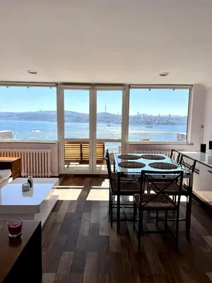 a living room with a table and chairs and the ocean at Deluxe Duplex in city center with 210 degrees Bosphorus viewed in Istanbul