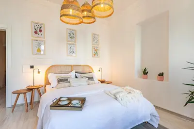a white bedroom with a large bed with two candles on a tray at Maison Istanbulite in Istanbul