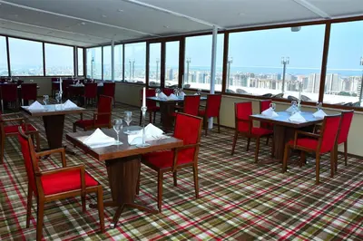 a restaurant with tables and red chairs and windows at Adranos Hotel in Bursa