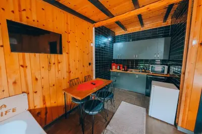 a kitchen with wooden walls and a wooden table and chairs at Sakarya Sapanca Memnuniye de 3 Oda1 salon Özel Havuzlu-Jakuzili-Şömineli-Korunaklı 8 Kişilik Bungalov in Sapanca