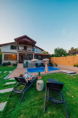 a woman laying in lawn chairs in front of a house at Sepetçi Lakehouse Heated Pool in Kartepe