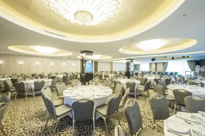 a banquet room with tables and chairs and a chandelier at Ramada by Wyndham Gemli̇k in Gemlik