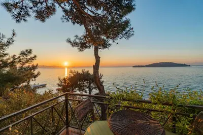 a sunset over the water with a table and an umbrella at Palais Büyükada in Adalar
