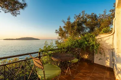 a balcony with a table and chairs next to the water at Palais Büyükada in Adalar