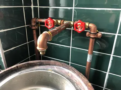 a metal toilet in a green tiled wall with pipes at Hendec 7 Apartments Near Galataport in Istanbul