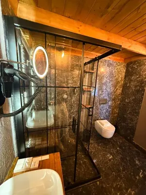 a bathroom with a glass shower with a toilet at Navy Inn & Bungalows in Arnavutköy