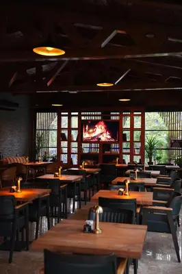 a restaurant with wooden tables and chairs and a tv at Navy Inn & Bungalows in Arnavutköy