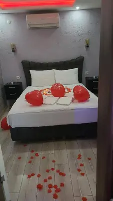 a bed with red pillows and flowers on the floor at HEVİN Otel in Bursa