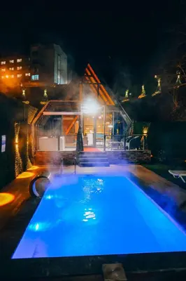 a large blue swimming pool at night with a building at Mert Bungalov-Yıldız Evi in Sapanca